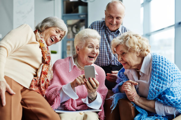 Eine Gruppe von älteren Menschen blickt lachend auf ein Smartphone